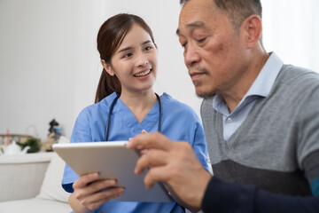 Fototapeta na wymiar Nurse and Asian senior man. Nurse using digital tablet discussing health insurance to Asian senior man at hospital. Retirement and health care concept