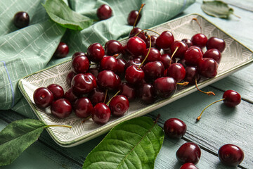 Plate with sweet cherries on blue wooden table