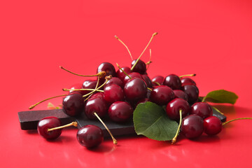 Board with sweet cherries on red background