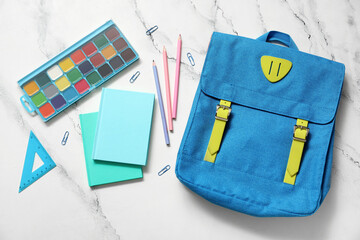 Blue school backpack with notebooks, watercolors and pencils on white grunge background