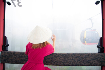 A woman tourist is staying on cable car while traveling on Bana Hill in Danang, Vietnam.