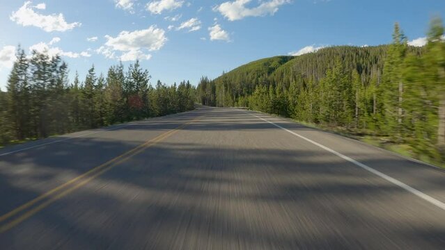 POV Driving a car on asphalt mountain road in Yellowstone National Park. Blue sky on sunny afternoon