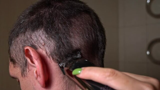Man haircut with clipper back view in slow mo. Barber giving short haircut to male client. Professional hairdresser cuts young guy's hair with clipper. Man hairdressing with electric shaver