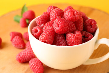 Cup and board with fresh raspberries, closeup