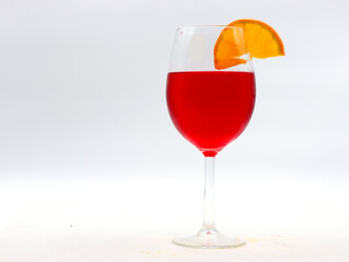 close-up of a goblet with red aperitif and orange slice on a white background