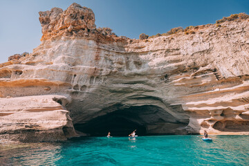 Group of sup boarders enters huge limestone cave on a sea coast