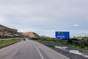 Beautiful summer landscape with highway among rocky mountains and dark blue sky with fluffy clouds on a summer day at sunset. American Roadscape with red canyons in New Mexico near Albuquerque, USA