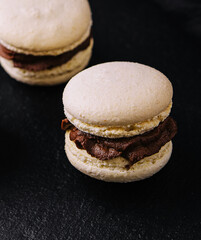 Caramel macarons with chocolate filling on black stone