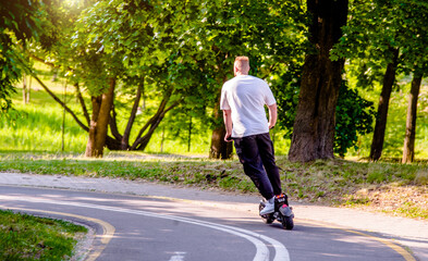 Fototapeta premium A guy rides an electric scooter in the summer Park