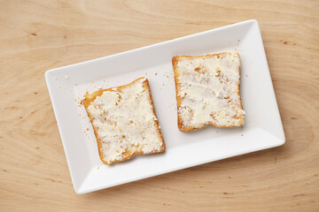 Toasts with butter on a ceramic plate, top view