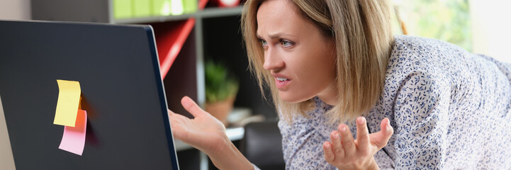 Upset woman looking at laptop screen with angry expression