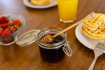 Close up of strawberries, jam, waffles and juice on wooden table