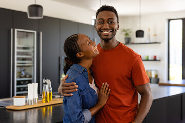 Portrait of happy african american couple embracing in kitchen