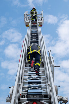 Des pompiers sur une grande &eacute;chelle et un ciel bleu avec des nuages