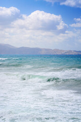 Sea view with wave, hills in the distance and cloudy sky in Crete