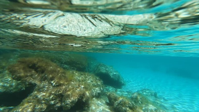 Underwater slow motion video of weaves of sunlight on the white sandy bottom