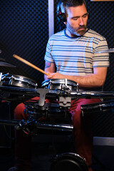 Drummer man playing drums with headphones in a recording studio. Music production.