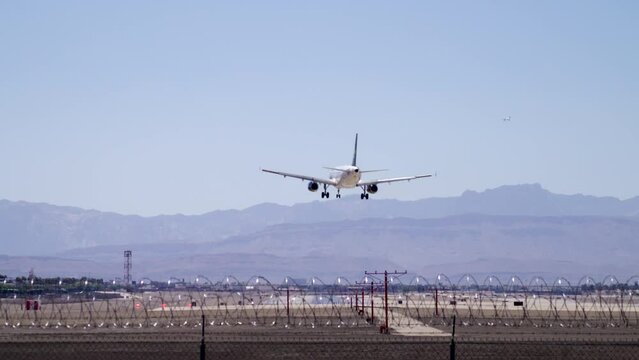 Slow motion shot of landing commercial jet, rear view from end of runway. Passenger plane touchdown with a beautiful scenery behind the window add Las Vegas airport Nevada USA