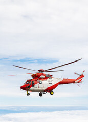 Rescue service on helicopter on volcano above the clouds. Blue sky line on horizon dark volcanic rocks on ground white and red helicopter. Vacation tour on helicopter