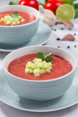 Gazpacho soup garnished with cucumber and cilantro, in bowl, vertical