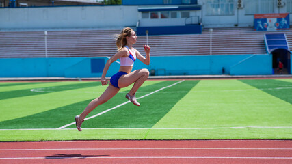 Young caucasian woman is engaged in jogging at the stadium outdoors.