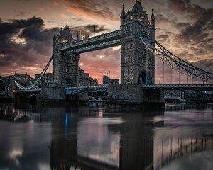 the sun sets on the london tower bridge as seen from the water