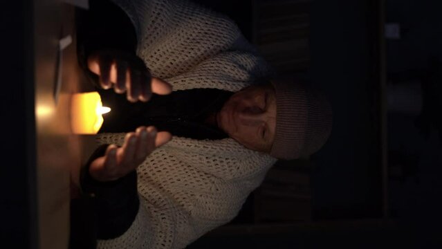 Old senior man without electricity at home with candle. Shutdown of heating and electricity, power outage, blackout, load shedding or energy crisis. copy space.