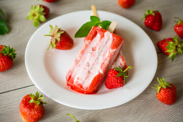 homemade strawberry ice cream on a stick in a plate with strawberries