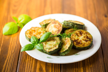 zucchini fried in circles with spices and herbs, in a plate .