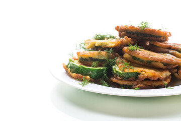 zucchini fried in circles in batter with herbs, in a plate.