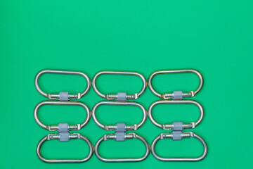 Many climbing metal carabiners on a green background as a texture, pattern, background