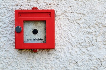 High-resolution closeup of a manual red fire detector positioned on the side of a white wall