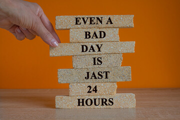 Inspirational quote Even a bad day is jast 24 hours on brick blocks. Beautiful orange background, wooden table. Motivational concept. Copy space.  