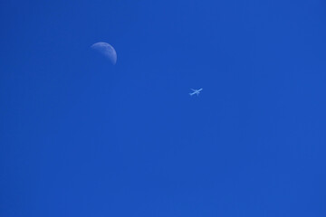an airplane flying near the moon in a cloudless sky