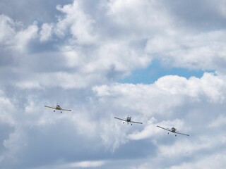 View of airplanes soaring in formation over a landscape of rolling hills and cloudy skies