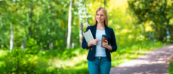 Young caucasian girl with wireless headphones in the park using tablet, phone and smiling