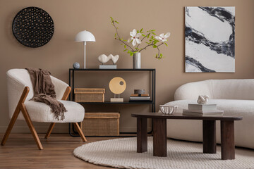 Warm and cozy living room interior with mock up poster frame, wooden coffee table, boucle sofa, white armchair, black rack, vase with magnolia, brown plaid and personal accessories. Template.