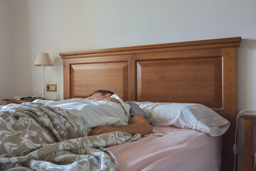 Fototapeta na wymiar Man sleeping comfortably in his bed at home