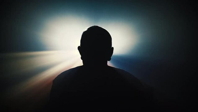 Silhouette of a person standing in front of the vintage projector light