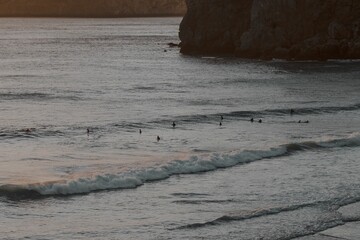 Group of surfers in the water in Algarve, Portugal, at sunset