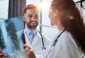 Young serious competent male doctor looking at X-ray at doctor's office