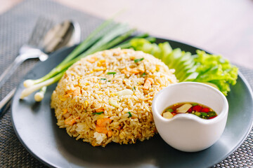 Salmon fried rice in black plate with spoon and fork.