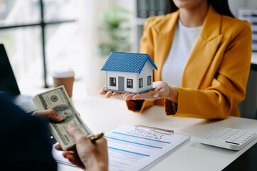 Fototapeta na wymiar Buying a home or insurance deal, an insurance agent pointing a pen to those interested in renting a house, a contract, signing an Home buying agreement in modern office.