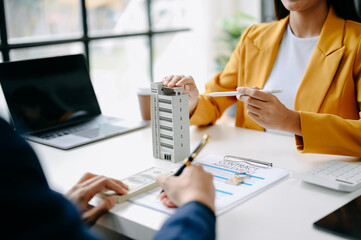 Buying a home or insurance deal, an insurance agent pointing a pen to those interested in renting a house, a contract, signing an Home buying agreement in modern office.