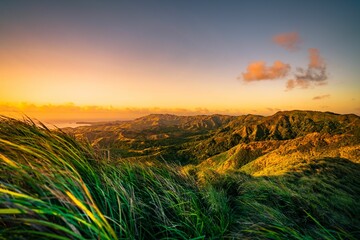 A beautiful sunset over a mountain range, with lush grass and vibrant colors, Guam - obrazy, fototapety, plakaty