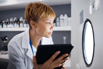 Scientist, tablet and woman in laboratory with incubator machine for test, analysis or research...