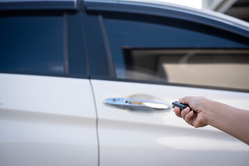 Female hand pushing remote key of white car