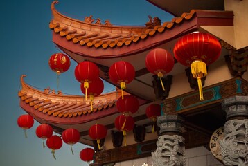 a chinese styled structure with red lanterns and stone columns in it