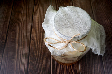 Kombucha.  on the right is a kombucha in a large glass jar with a gauze white lid tied with a thick thread.  the process of making a summer drink.  view from above. copy space