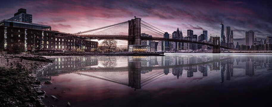 Panoramic view of the Brooklyn Bridge and the Manhattan skyline at sunset.